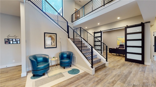 481 Comanche Rd, Lake Ozark, MO 65049 - stairway with a barn door, a high ceiling, wood finished floors, and baseboards