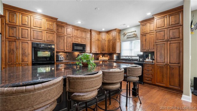 149 Snead Cir, Lake Ozark, MO 65049 - kitchen featuring black appliances, backsplash, dark wood-type flooring, a breakfast bar area, and recessed lighting