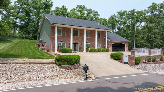 149 Snead Cir, Lake Ozark, MO 65049 - neoclassical home featuring concrete driveway, brick siding, a garage, and view of wooded area