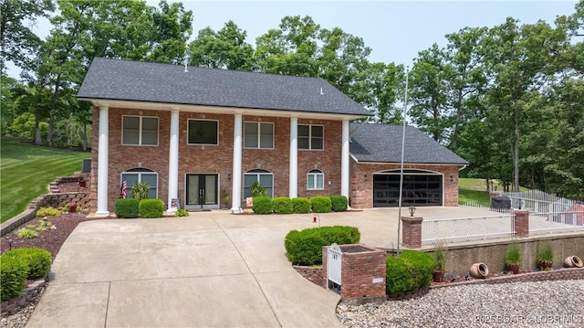 149 Snead Cir, Lake Ozark, MO 65049 - neoclassical / greek revival house featuring curved driveway, a garage, brick siding, roof with shingles, and a front lawn