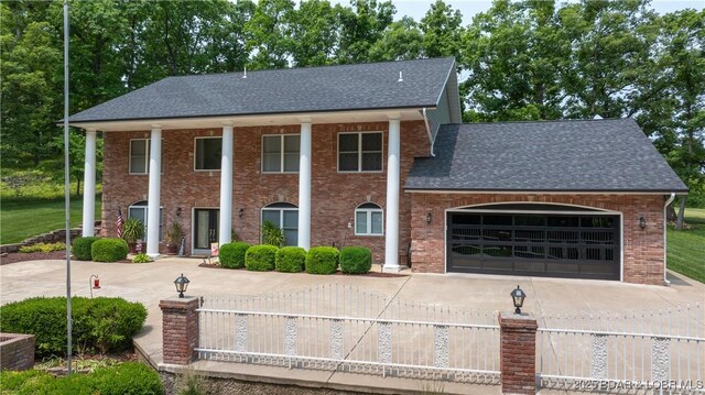 149 Snead Cir, Lake Ozark, MO 65049 - greek revival inspired property featuring driveway, roof with shingles, a garage, and brick siding