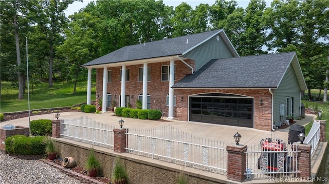149 Snead Cir, Lake Ozark, MO 65049 - greek revival house featuring an attached garage, brick siding, a shingled roof, and concrete driveway