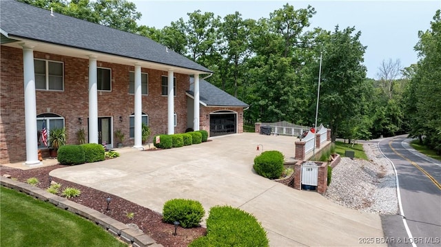 149 Snead Cir, Lake Ozark, MO 65049 - view of front of home with brick siding, concrete driveway, a garage, and roof with shingles