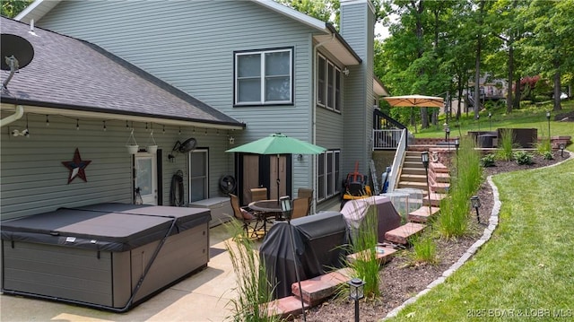 149 Snead Cir, Lake Ozark, MO 65049 - back of property with a hot tub, stairway, a chimney, a patio, and a yard