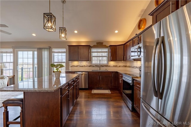 4715 Inlet Ln, Osage Beach, MO 65065 - kitchen with appliances with stainless steel finishes, dark wood-style floors, a kitchen bar, backsplash, and a center island