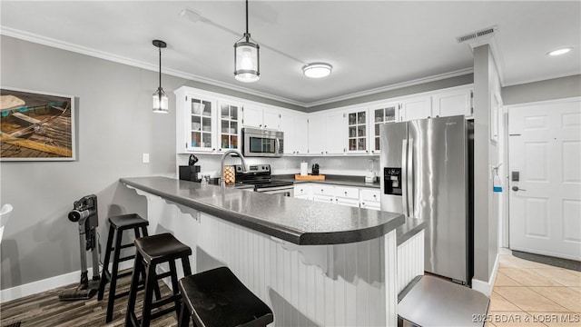 4897 Bridgepoint Dr Unit 311, Osage Beach, MO 65065 - kitchen with appliances with stainless steel finishes, a peninsula, dark countertops, ornamental molding, and glass insert cabinets