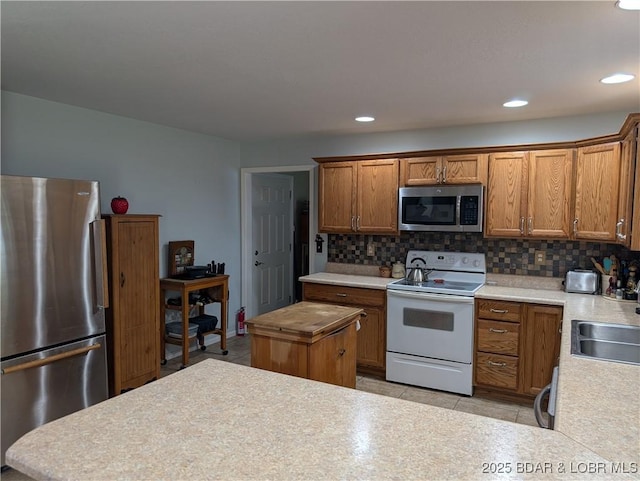 1001 Ha Ha Tonka Rd, Camdenton, MO 65020 - kitchen featuring stainless steel appliances, decorative backsplash, light countertops, brown cabinets, and recessed lighting