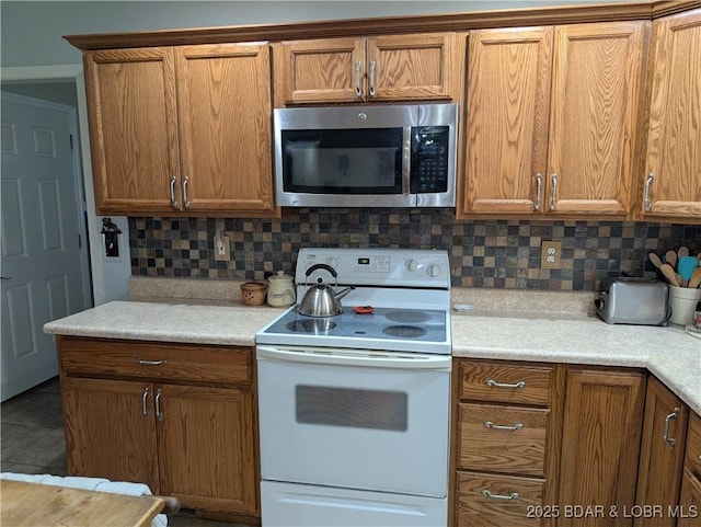 1001 Ha Ha Tonka Rd, Camdenton, MO 65020 - kitchen with stainless steel microwave, white electric range oven, brown cabinets, and decorative backsplash