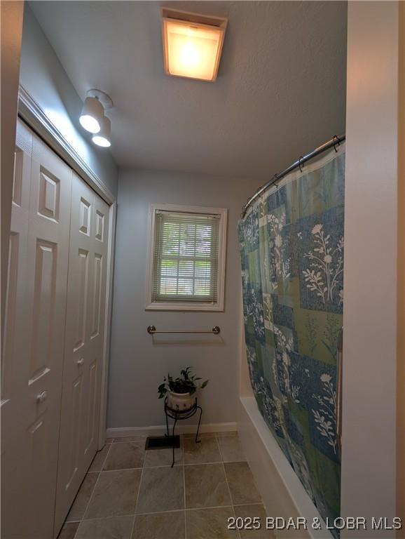1001 Ha Ha Tonka Rd, Camdenton, MO 65020 - full bathroom with tile patterned floors, baseboards, and shower / bathtub combination with curtain