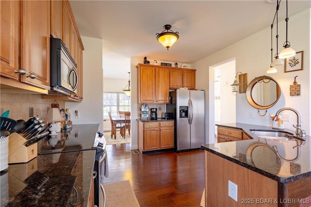 915 Bear Cave Way, Camdenton, MO 65020 - kitchen featuring appliances with stainless steel finishes, a sink, dark wood finished floors, brown cabinets, and backsplash