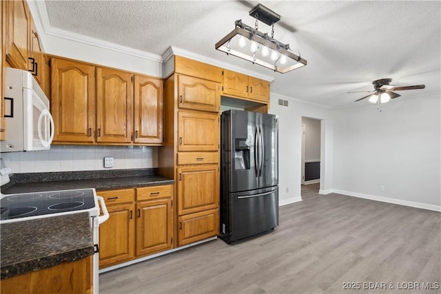 107 Haynes St, Eldon, MO 65026 - kitchen with white appliances, ceiling fan, backsplash, brown cabinets, and ornamental molding