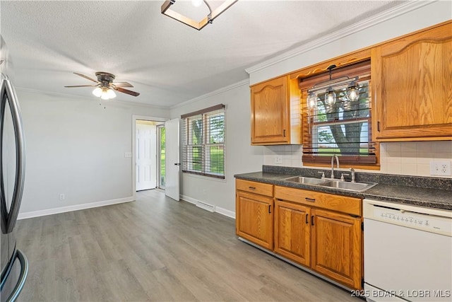 107 Haynes St, Eldon, MO 65026 - kitchen featuring white dishwasher, a sink, ornamental molding, freestanding refrigerator, and tasteful backsplash