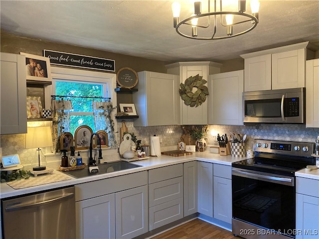 301 Burke St, Versailles, MO 65084 - kitchen featuring stainless steel appliances, a sink, light countertops, a chandelier, and tasteful backsplash