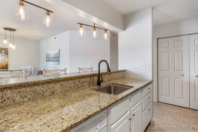4800 Eagleview Dr Unit 115B, Osage Beach, MO 65065 - kitchen featuring a sink, light tile patterned floors, white cabinetry, decorative light fixtures, and light stone counters