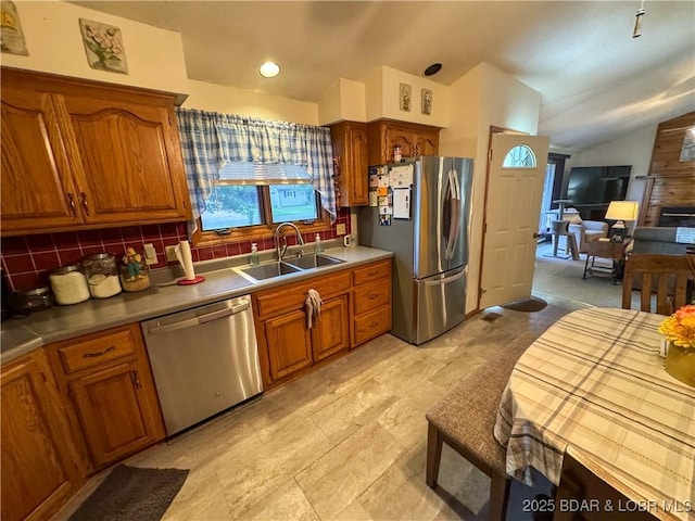 104 Tower View Dr, Versailles, MO 65084 - kitchen with stainless steel appliances, a sink, brown cabinets, lofted ceiling, and decorative backsplash