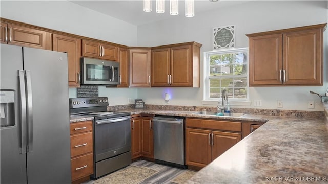 166 Joy Cir, Camdenton, MO 65020 - kitchen with stainless steel appliances, a sink, brown cabinetry, and light wood-type flooring