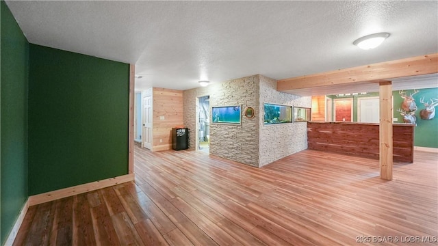166 Joy Cir, Camdenton, MO 65020 - unfurnished living room with wood finished floors, baseboards, a textured ceiling, wood walls, and a stone fireplace