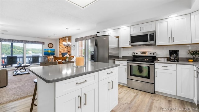 149 Sycamore Beach Rd Unit C1, Camdenton, MO 65020 - kitchen featuring appliances with stainless steel finishes, open floor plan, light wood-style flooring, dark countertops, and white cabinetry