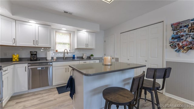 149 Sycamore Beach Rd Unit C1, Camdenton, MO 65020 - kitchen with stainless steel dishwasher, a sink, light wood-type flooring, a breakfast bar area, and dark countertops