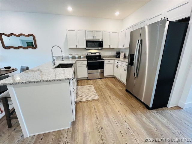295 Highland Shores Dr Unit 2D, Lake Ozark, MO 65049 - kitchen with appliances with stainless steel finishes, a sink, a peninsula, light stone countertops, and light wood-type flooring