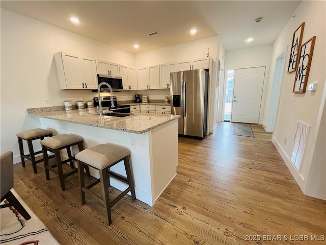 295 Highland Shores Dr Unit 2D, Lake Ozark, MO 65049 - kitchen with stainless steel appliances, a peninsula, a sink, light wood finished floors, and recessed lighting