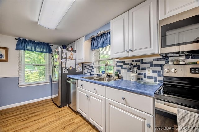 15852 Kindling Rd, Eldridge, MO 65463 - kitchen featuring appliances with stainless steel finishes, a sink, decorative backsplash, and light wood-style flooring