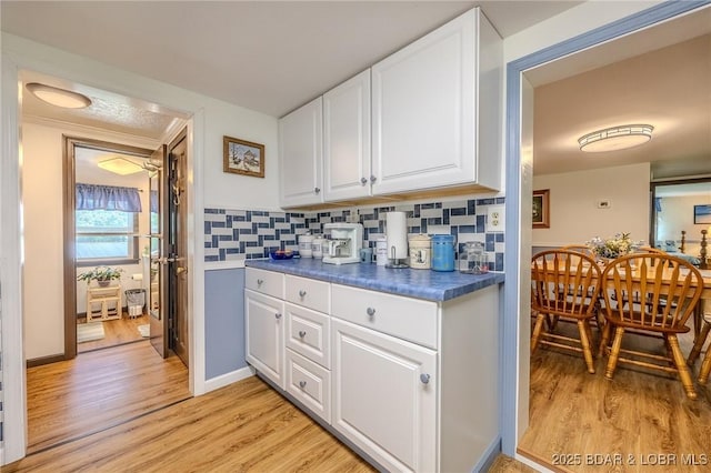 15852 Kindling Rd, Eldridge, MO 65463 - kitchen with dark countertops, light wood-style floors, white cabinets, and tasteful backsplash