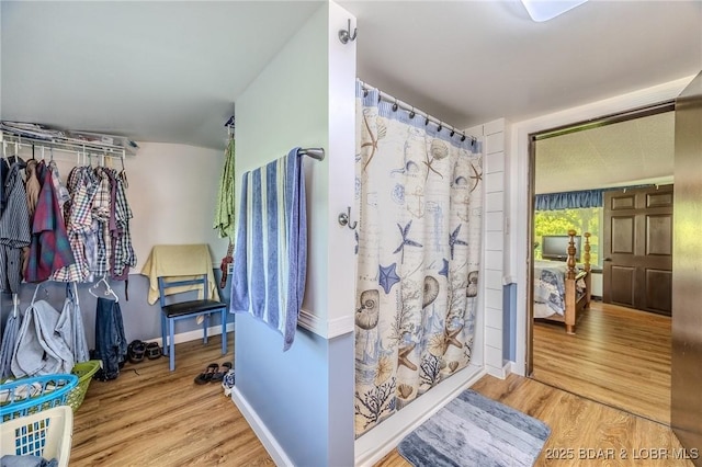 15852 Kindling Rd, Eldridge, MO 65463 - full bathroom featuring wood finished floors, a shower with shower curtain, baseboards, and a spacious closet