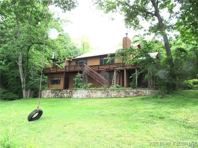 rear view of property with a chimney, a deck, a yard, and stairs