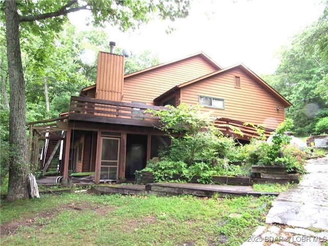 back of house featuring a chimney and a wooden deck