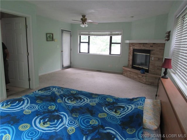 carpeted living room with ceiling fan, a glass covered fireplace, and baseboards