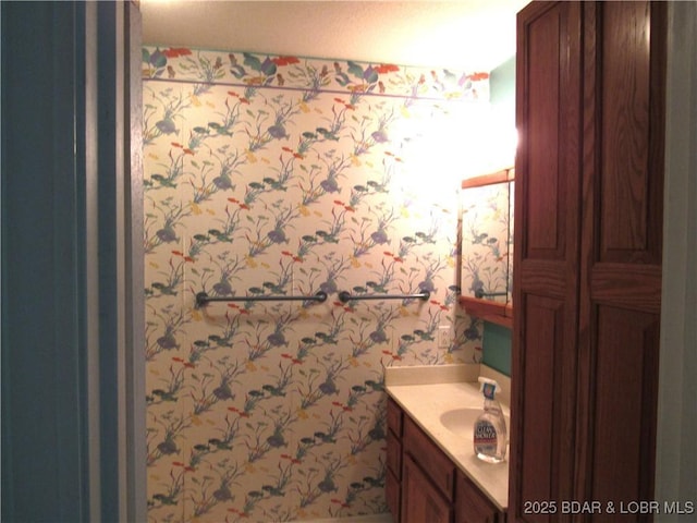 bathroom with vanity and wallpapered walls