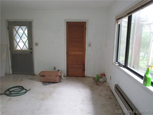 entrance foyer with healthy amount of natural light, unfinished concrete floors, and a baseboard radiator