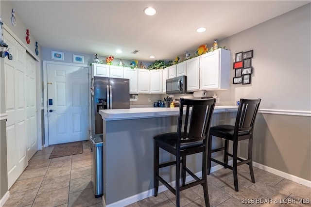 549 Park Place Dr Unit 2D, Kaiser, MO 65047 - kitchen featuring black microwave, stainless steel fridge, a peninsula, light countertops, and white cabinetry