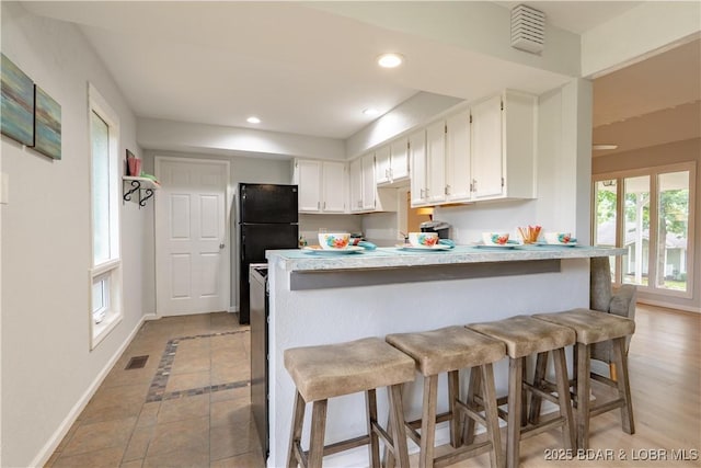 1556 Mockingbird Ln, Osage Beach, MO 65065 - kitchen with a peninsula, baseboards, recessed lighting, a kitchen breakfast bar, and light countertops