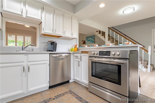 1556 Mockingbird Ln, Osage Beach, MO 65065 - kitchen with stainless steel appliances, white cabinetry, light countertops, a sink, and recessed lighting