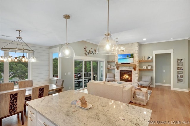 152 Pearl Ln, Climax Springs, MO 65324 - kitchen featuring light stone counters, crown molding, white cabinets, a stone fireplace, and decorative light fixtures