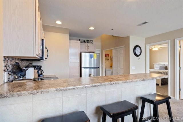 1481 Ledges Dr Unit 1047, Osage Beach, MO 65065 - kitchen featuring appliances with stainless steel finishes, a peninsula, a kitchen bar, light countertops, and recessed lighting