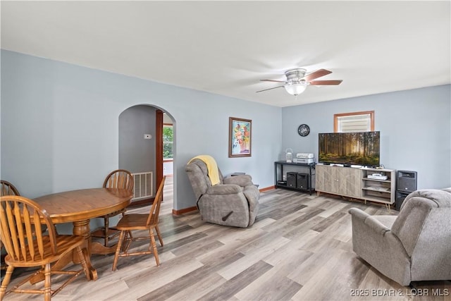 320 N Chestnut St, Eldon, MO 65026 - living room featuring arched walkways, a ceiling fan, light wood-style floors, and baseboards