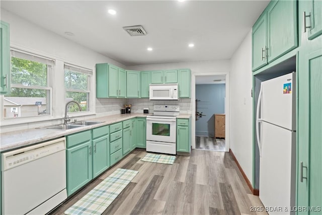 320 N Chestnut St, Eldon, MO 65026 - kitchen with white appliances, a sink, light wood finished floors, light countertops, and tasteful backsplash
