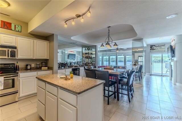 757 Malibu Rd Unit A102, Osage Beach, MO 65065 - kitchen with appliances with stainless steel finishes, a center island, white cabinetry, light stone counters, and wine cooler