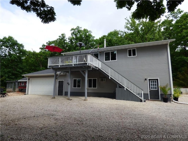 31762 Pecan Dr, Rocky Mount, MO 65072 - rear view of property featuring an attached garage, stairway, a wooden deck, and gravel driveway