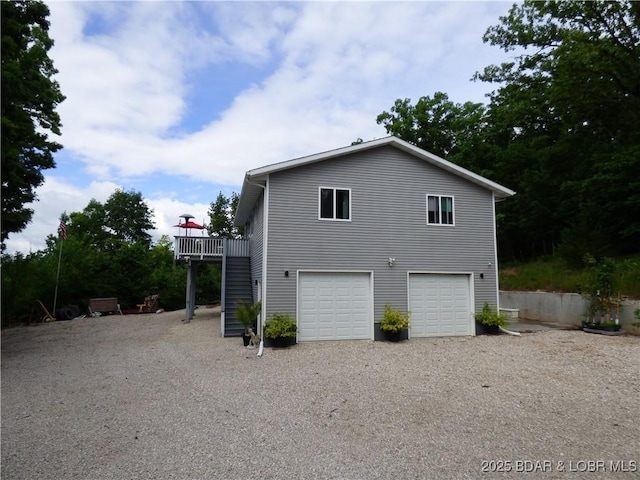 31762 Pecan Dr, Rocky Mount, MO 65072 - view of property exterior featuring gravel driveway, an attached garage, a wooden deck, and stairs