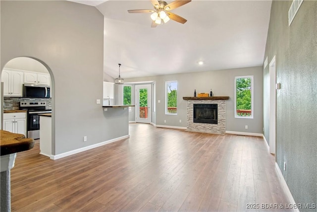 1380 Bluff Dr, Osage Beach, MO 65065 - unfurnished living room with healthy amount of natural light, a fireplace, ceiling fan, vaulted ceiling, and baseboards