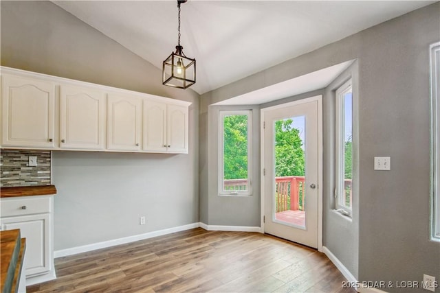 1380 Bluff Dr, Osage Beach, MO 65065 - unfurnished dining area with light wood-style flooring, lofted ceiling, and baseboards