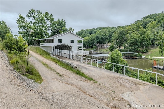 29 Vine St, Edwards, MO 65326 - view of front of house featuring dirt driveway, a detached carport, a dock, a water view, and boat lift