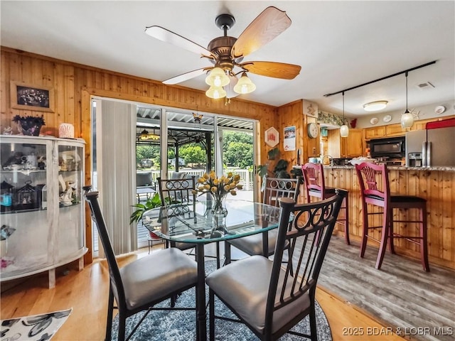 590 Jupiter Rd, Camdenton, MO 65020 - dining room with wood walls, ceiling fan, and light wood finished floors