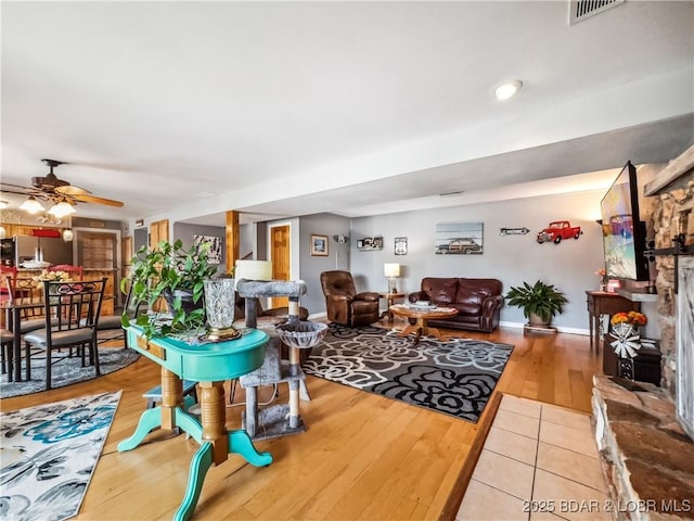 590 Jupiter Rd, Camdenton, MO 65020 - living room featuring a ceiling fan, a stone fireplace, and light wood-type flooring