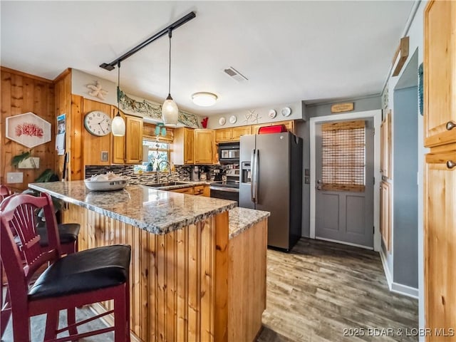 590 Jupiter Rd, Camdenton, MO 65020 - kitchen featuring appliances with stainless steel finishes, a peninsula, light stone counters, light wood-type flooring, and pendant lighting