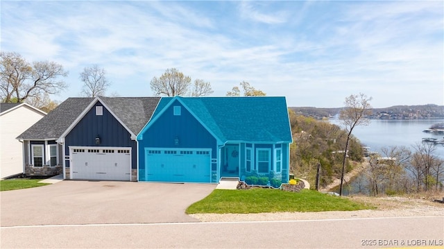 23 Enclaves Ln, Lake Ozark, MO 65049 - view of front of home with board and batten siding, asphalt driveway, an attached garage, a front yard, and a water view